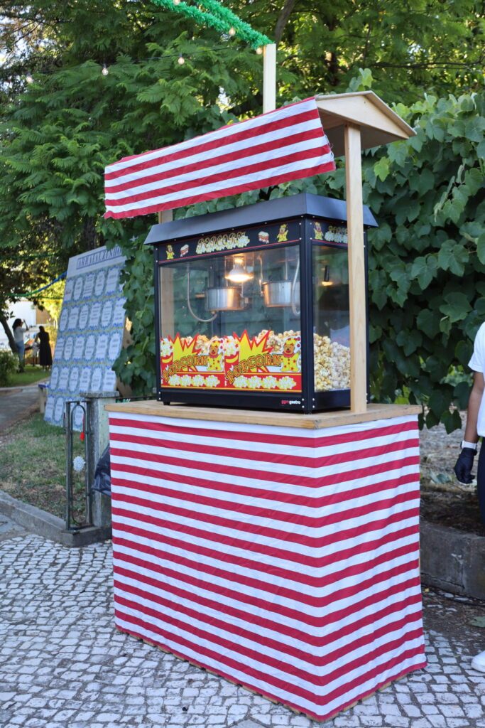 Decoração de arraial com bandeirola às riscas vermelhas e brancas e luzes entre a folhagem